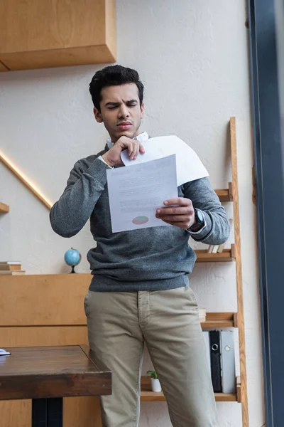 Selective focus of worried businessman looking at paper in office — Stock Photo