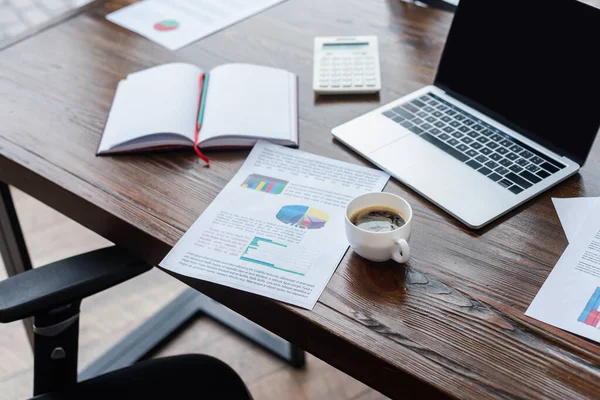 Selektiver Fokus der Tasse Kaffee in der Nähe von Zeitungen, Laptop und Notebook auf dem Tisch im Büro — Stockfoto