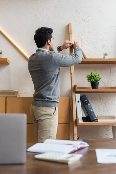 Selektiver Fokus von Geschäftsleuten, die im Büro Bücher aus den Regalen holen — Stockfoto