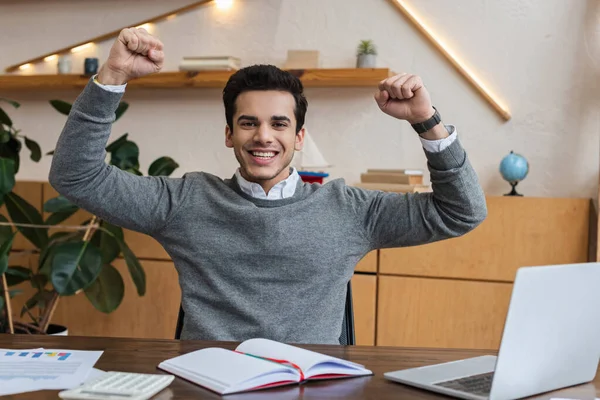 Aufgeregter Geschäftsmann blickt in die Kamera und lächelt am Tisch im Büro — Stockfoto