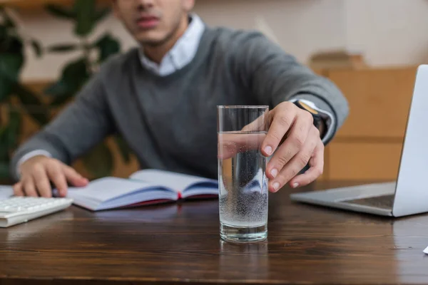 Ausgeschnittene Ansicht eines Geschäftsmannes, der im Amt ein Glas Wasser trinkt — Stockfoto