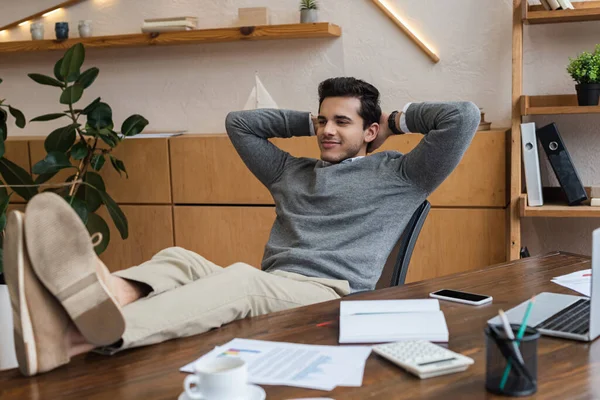 Businessman with hands behind head put legs on table in office — Stock Photo