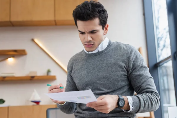 Uomo d'affari preoccupato con matita che guarda la carta in ufficio — Foto stock