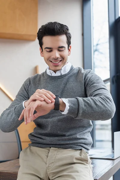 Geschäftsmann schaut auf Armbanduhr und lächelt im Büro — Stockfoto