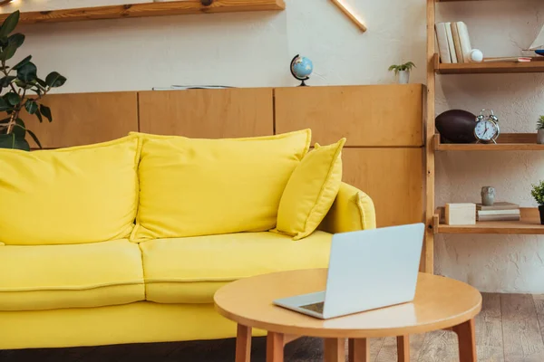 Кофейный столик с ноутбуком возле дивана в гостиной — стоковое фото