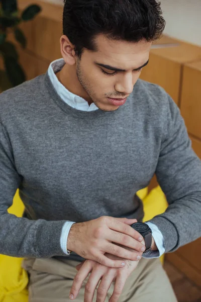 High angle view of man looking at wristwatch in living room — Stock Photo