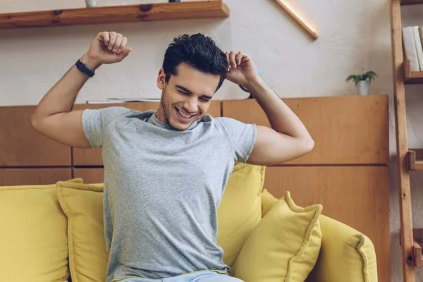 Man stretching himself and smiling on sofa in living room — Stock Photo