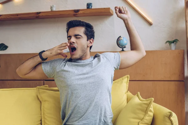 Homme s'étirant et bâillant sur le canapé dans le salon — Photo de stock