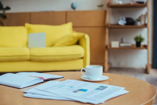 Mesa de café com papéis, xícara de café e caderno na sala de estar — Fotografia de Stock