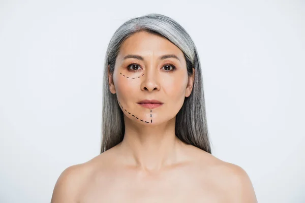 Atractiva mujer asiática desnuda con líneas de cirugía plástica en la cara aislada en gris - foto de stock