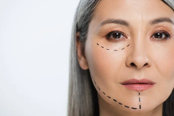 Азіатська жінка з лініями пластичної хірургії на обличчі ізольована на сірому — стокове фото
