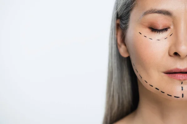 Mezza vista del viso di donna asiatica con linee di chirurgia plastica isolate su grigio — Foto stock