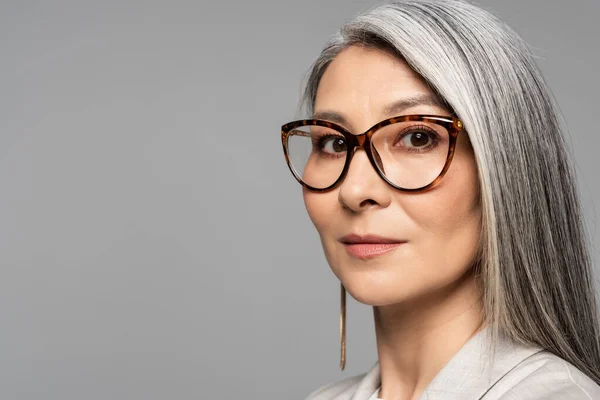 Приваблива азіатська бізнес-леді в окулярах ізольована на сірому — стокове фото
