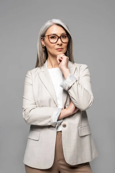Nachdenkliche professionelle asiatische Geschäftsfrau mit Brille isoliert auf grau — Stockfoto