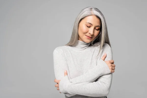 Femme asiatique rêveuse au col roulé avec les cheveux gris et les yeux fermés isolés sur gris — Photo de stock