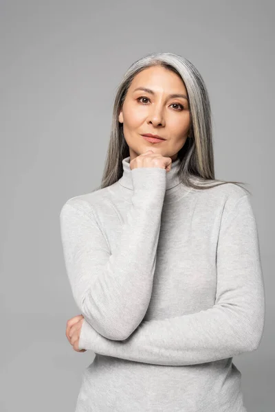 Femme asiatique réfléchie à col roulé avec les cheveux gris et les yeux fermés isolé sur gris — Photo de stock