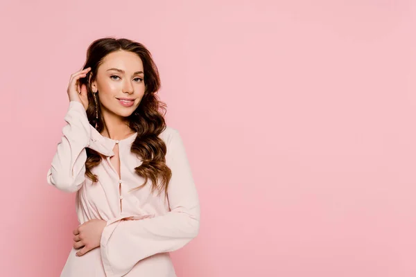 Pretty girl smiling and touching hair isolated on pink — Stock Photo