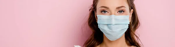 Панорамный снимок девушки в медицинской маске, изолированной на розовом — стоковое фото