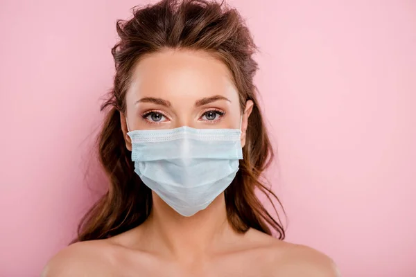 Jeune femme en masque médical regardant la caméra isolée sur rose — Photo de stock