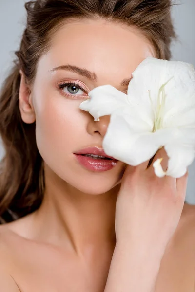 Attractive woman covering face with white blooming flower isolated on grey — Stock Photo
