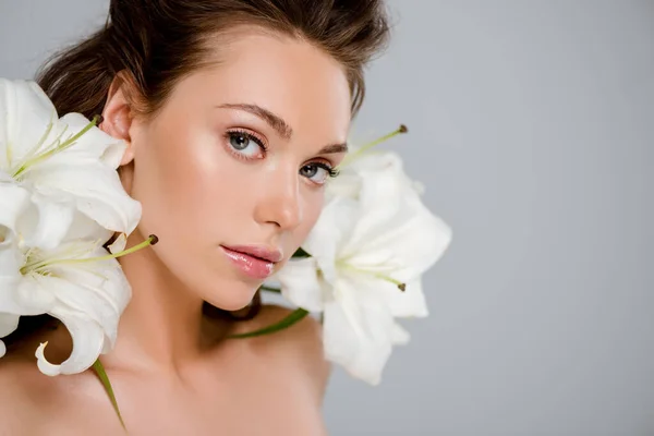 Junge attraktive Frau in der Nähe von weiß blühenden Blumen isoliert auf grau — Stockfoto