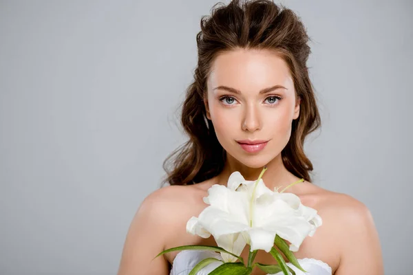 Jovem bela mulher olhando para a câmera perto de flor branca isolada no cinza — Fotografia de Stock