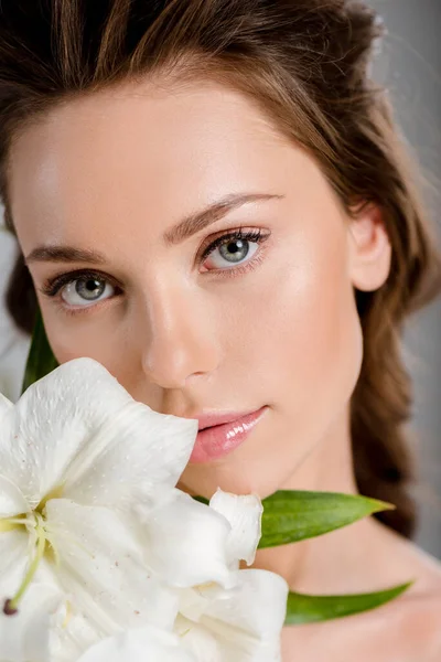 Hübsche Frau blickt in die Kamera neben weißen Blumen — Stockfoto