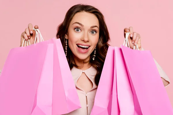 Весела молода жінка тримає сумки ізольовані на рожевому — стокове фото