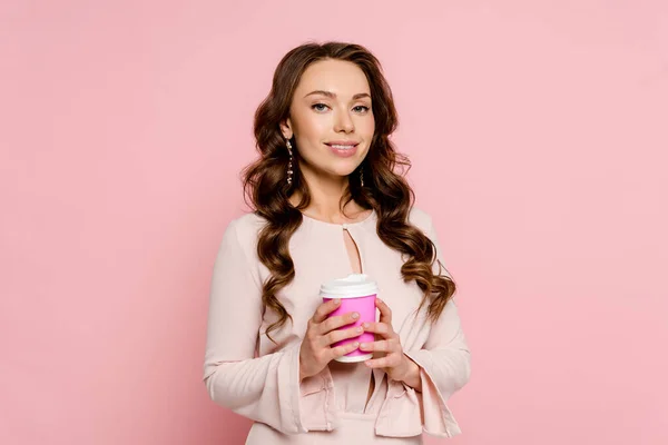 Glückliche junge Frau hält Pappbecher isoliert auf rosa — Stockfoto
