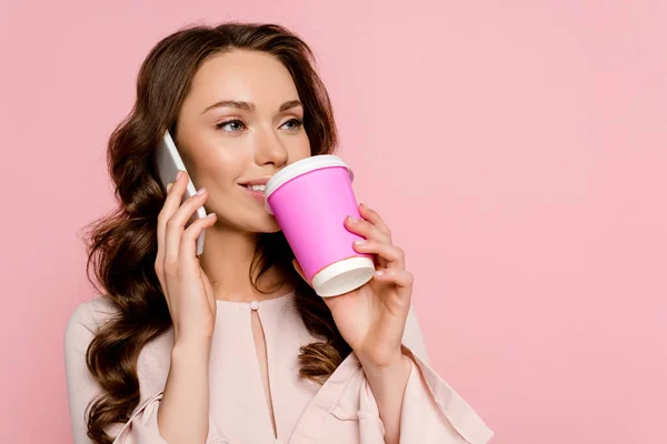 Chica feliz hablando en el teléfono inteligente y beber café para ir aislado en rosa - foto de stock
