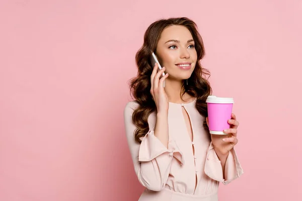 Fröhliches Mädchen spricht auf Smartphone und hält Pappbecher auf rosa — Stockfoto