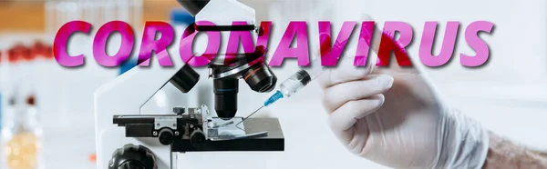 Partial view of biologist in latex gloves holding syringe near microscope, panoramic shot, coronavirus illustration — Stock Photo