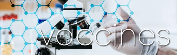 Частичный обзор биолога в латексных перчатках, держащего шприц возле микроскопа, панорамный снимок, иллюстрация вакцин — стоковое фото