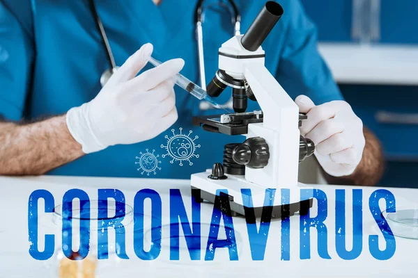 Ausgeschnittene Ansicht des Arztes in Latexhandschuhen mit Spritze in der Nähe des Mikroskops, Coronavirus-Illustration — Stockfoto