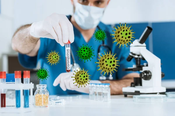 Enfoque selectivo del científico en máscara médica y guantes de látex que sostienen el tubo de ensayo con inscripción de coronavirus, ilustración de bacterias - foto de stock