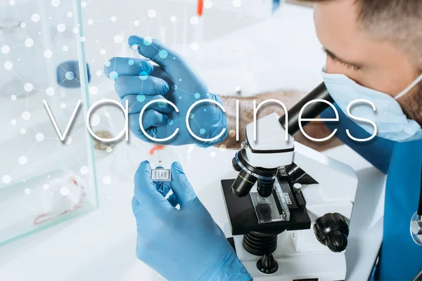 Молодий біолог у медичній масці та рукавичках, що тримають шприц під час аналізу мікроскопом біля білої миші у скляній коробці, ілюстрація вакцин — стокове фото
