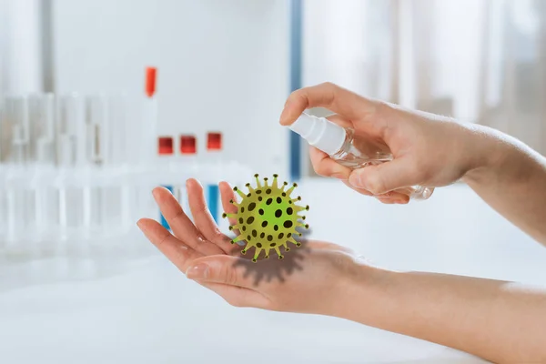 Ausgeschnittene Ansicht eines Arztes, der antiseptische Mittel auf Hände in der Nähe von Reagenzgläsern sprüht, Bakterien-Illustration — Stockfoto