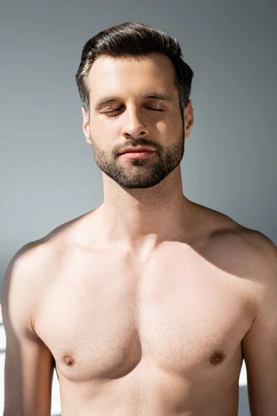 Hombre sin camisa y guapo con los ojos cerrados en gris - foto de stock