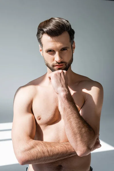 Shirtless and handsome man looking at camera and touching face on grey — Stock Photo