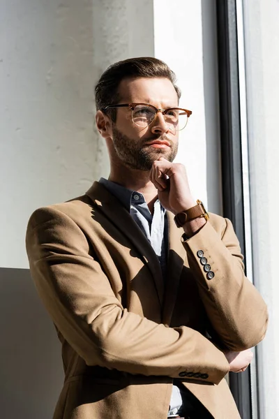 Pensativo hombre de negocios en gafas tocando la cara - foto de stock