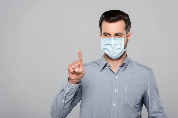 Uomo d'affari in maschera medica che punta con dito isolato su grigio — Foto stock