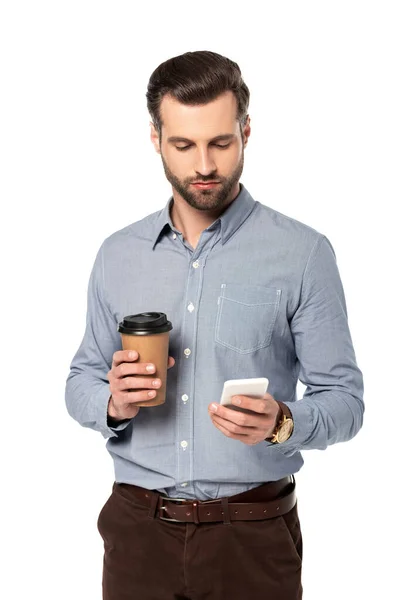 Bonito homem segurando café para ir e usando smartphone isolado no branco — Fotografia de Stock
