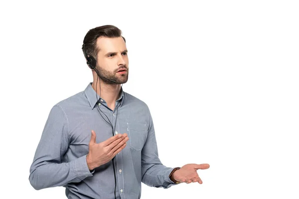 Operador guapo en auriculares hablando y haciendo gestos aislados en blanco - foto de stock