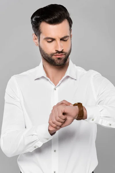 Homem de negócios bonito em camisa branca olhando para relógio isolado em cinza — Fotografia de Stock