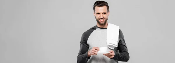 Панорамний знімок щасливого бородатого чоловіка, що тримає чашку кави ізольовано на сірому — стокове фото