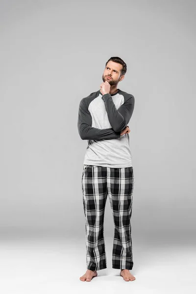 Pensive man touching face while standing on grey — Stock Photo