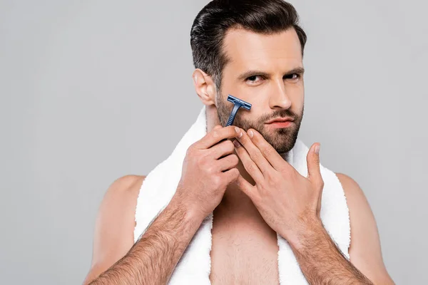Gutaussehender und bärtiger Mann rasiert sich isoliert auf grau — Stockfoto