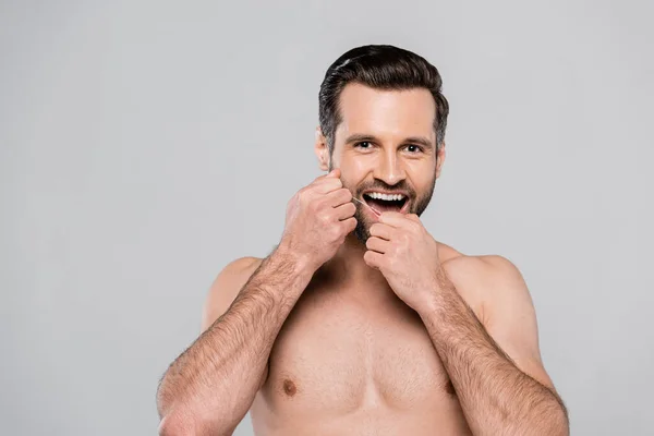 Homem feliz e muscular segurando fio dental isolado em cinza — Fotografia de Stock