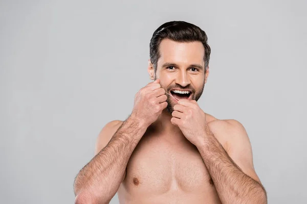 Hombre feliz y musculoso sosteniendo hilo dental aislado en gris — Stock Photo