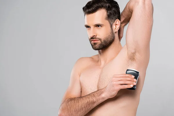 Handsome and muscular man applying solid stick deodorant isolated on grey — Stock Photo